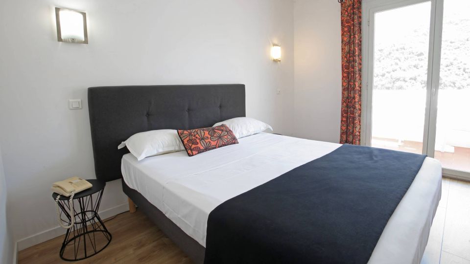 Confort Chambre moderne avec un grand lit, des lumières douces et un balcon offrant une belle vue. Ambiance tranquille.