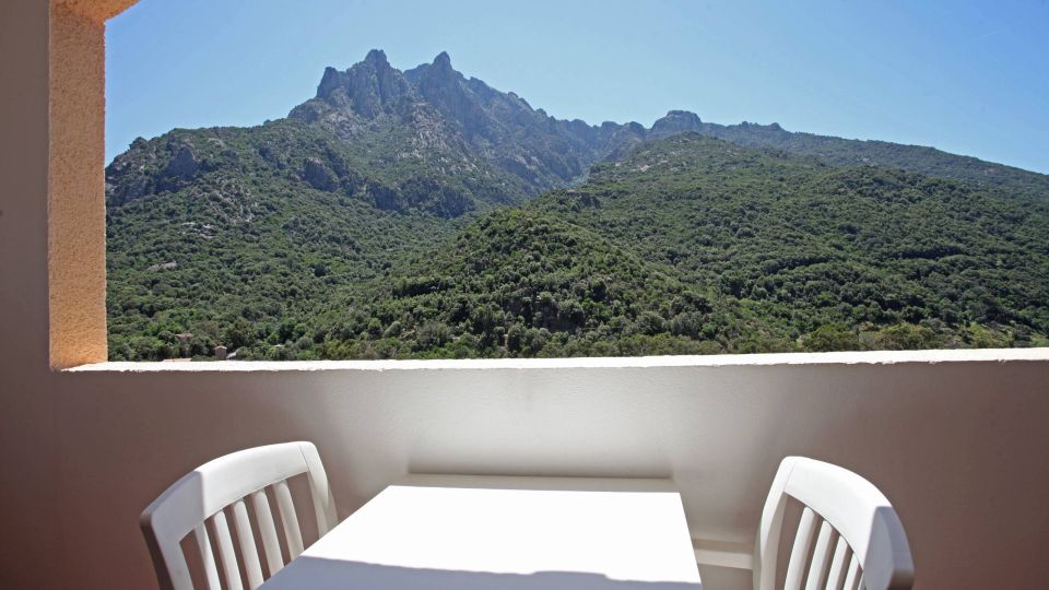 Confort Une vue magnifique des montagnes verdoyantes depuis un balcon avec une table et des chaises blanches.