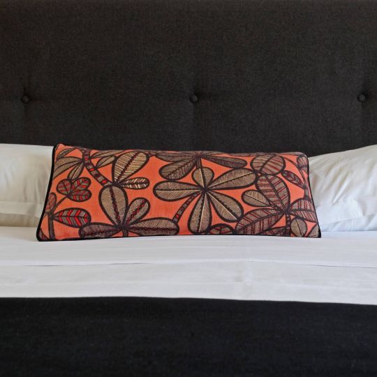 Confort Un lit moderne avec un coussin décoratif aux motifs de feuilles et un headboard noir élégant.