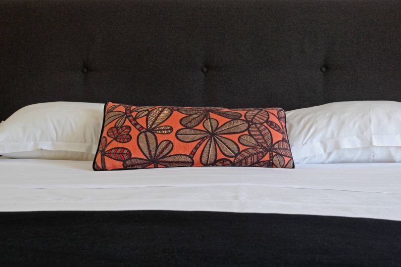 Confort Un lit moderne avec un coussin décoratif aux motifs de feuilles et un headboard noir élégant.