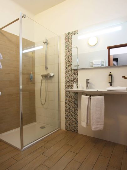 Confort Salle de bain moderne avec douche vitrée, carrelage clair et lavabo pratique. Atmosphère propre et accueillante.