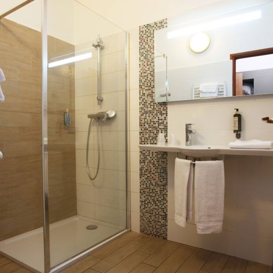 Confort Salle de bain moderne avec douche vitrée, carrelage clair et lavabo pratique. Atmosphère propre et accueillante.